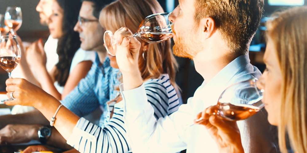 Grupo de personas en una cata de vino analizando la fase gustativa y compartiendo impresiones en una bodega.